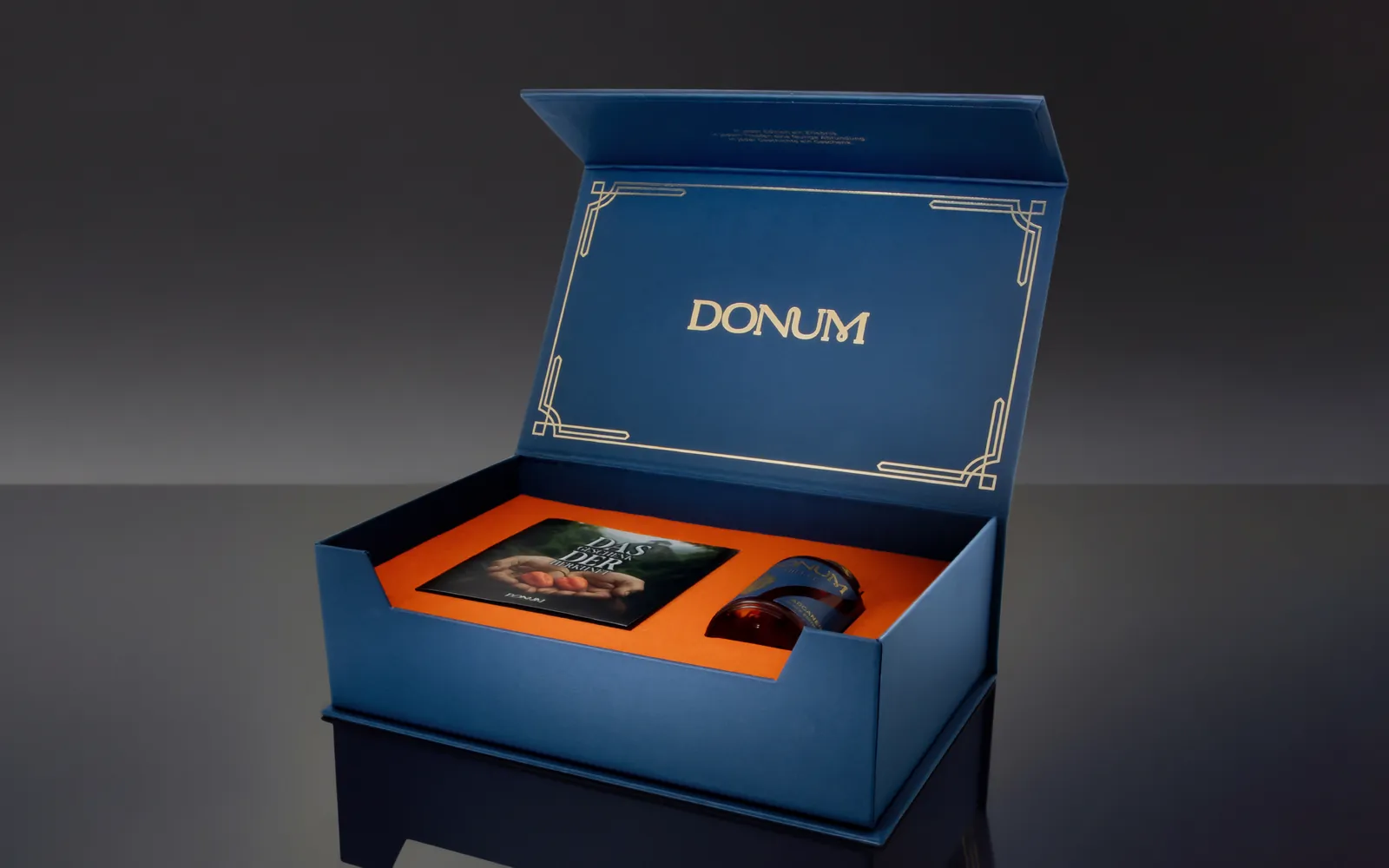 Die geoeffnete DONUM Geschenkbox der Black Edition mit Booklet und Flakon